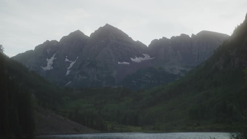 A serene lake lies at the foot of a majestic mountain range