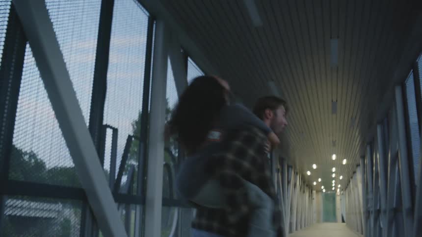 Man carrying his girlfriend on his back as they walk down a hallway