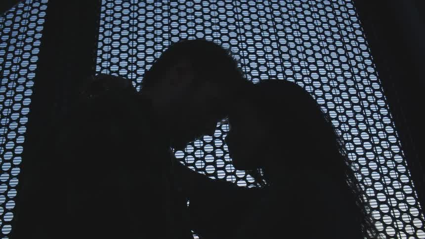 Silhouette of a man and a woman with their heads resting against each other in a romantic moment