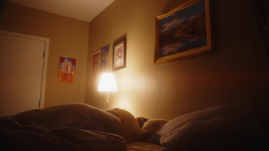A person lays in bad with the lamp on