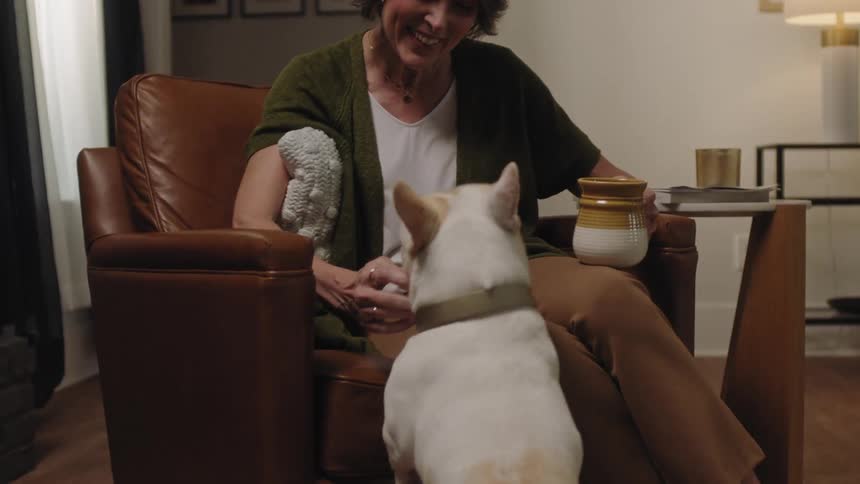 Woman sitting in an armchair petting her whitehaired dog