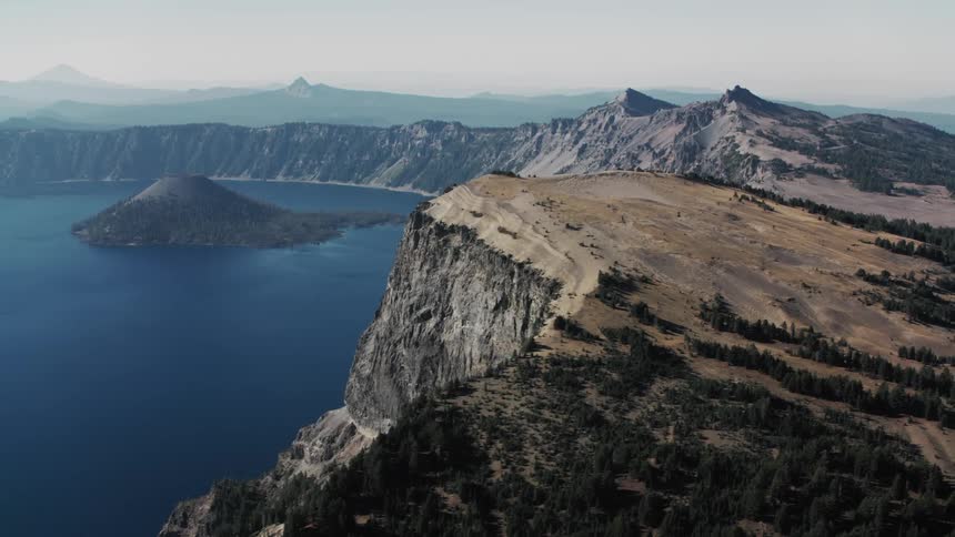 Aerial view of crater lake national park with the deep blue waters of the lake contrasting dramatically with the surrounding rocky cliffs and distant mountains