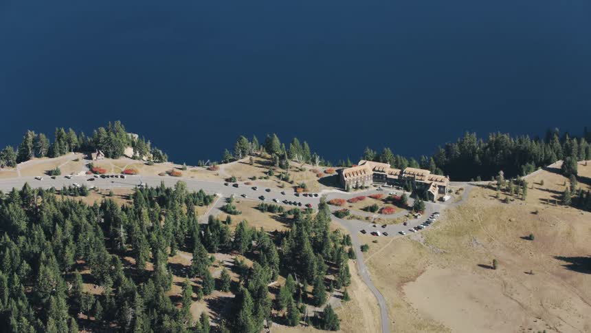 Cluster of water front buildings stands among conifer groves and yellowing fields of grass