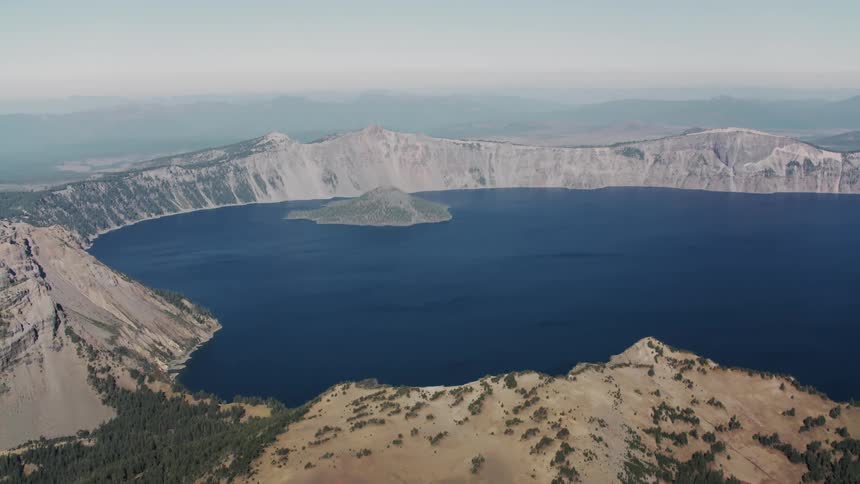 The deep blue waters of crater lake fill the caldera surrounded by steep cliffs