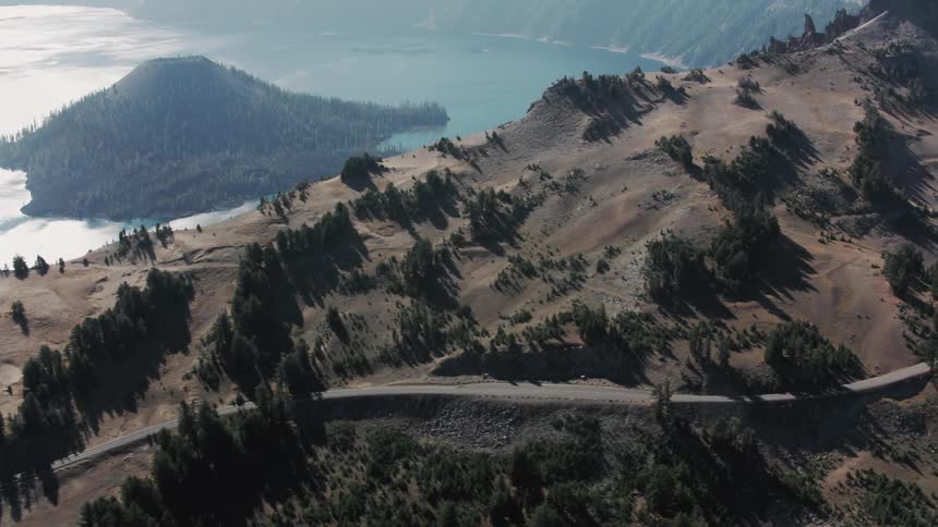 A winding road hugs the edge of a volcanic crater offering stunning views of the deep blue lake within