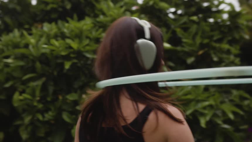 Woman with headphones and spinning with hula hoop on her body