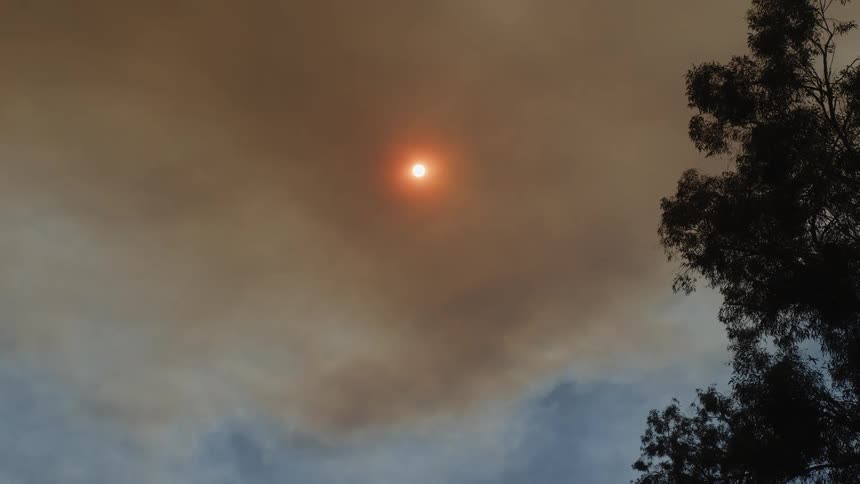 Sun appears partially covered by a dense layer of orange smoke in the sky