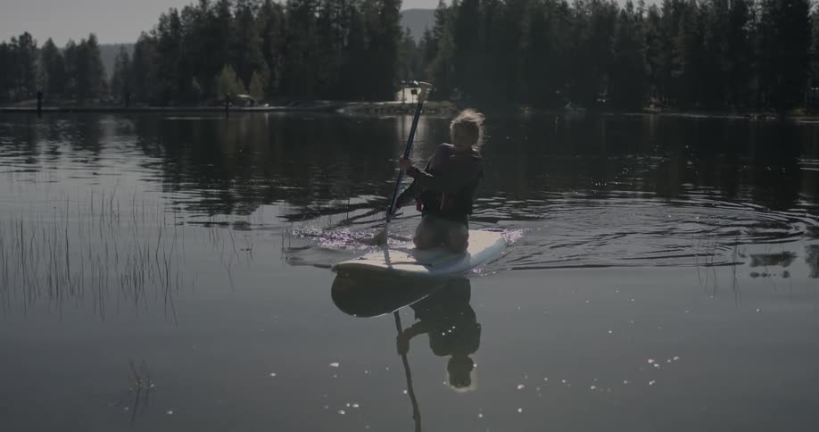 A girl is paddling towards the shore on a sunny day
