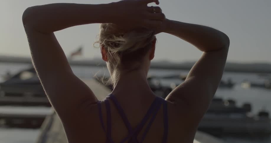 Woman puts her hair up on a windy day by the water