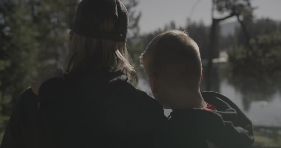 Two people hug near a lake