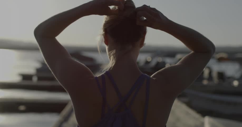 A woman ties her hair up in a bun