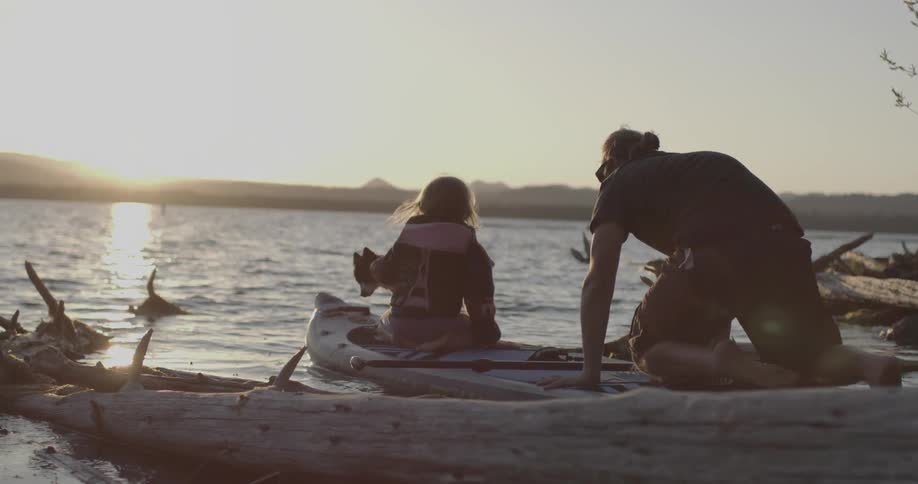 Couple and their dog aboard a small boat leaving the shore at sunset