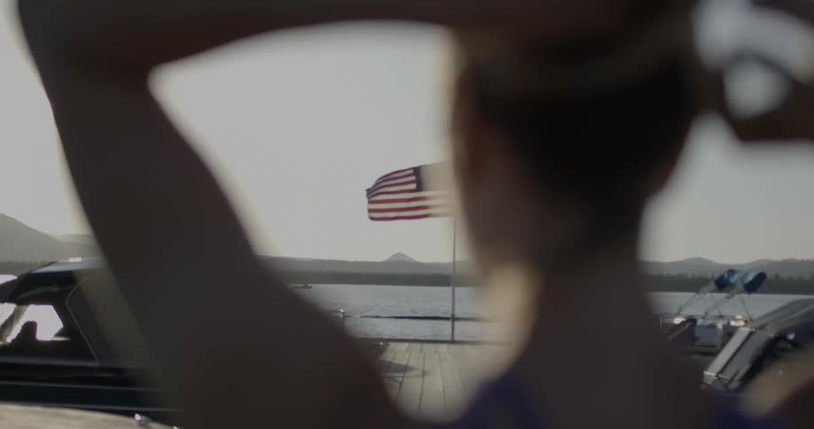 A view of the american flag through the arms of a woman fixing her hair