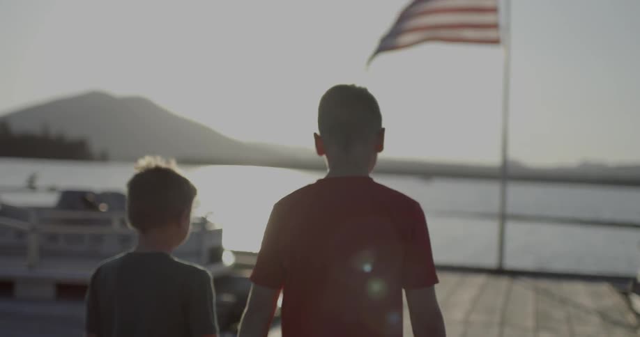 Two young boys are walking on a boat dock