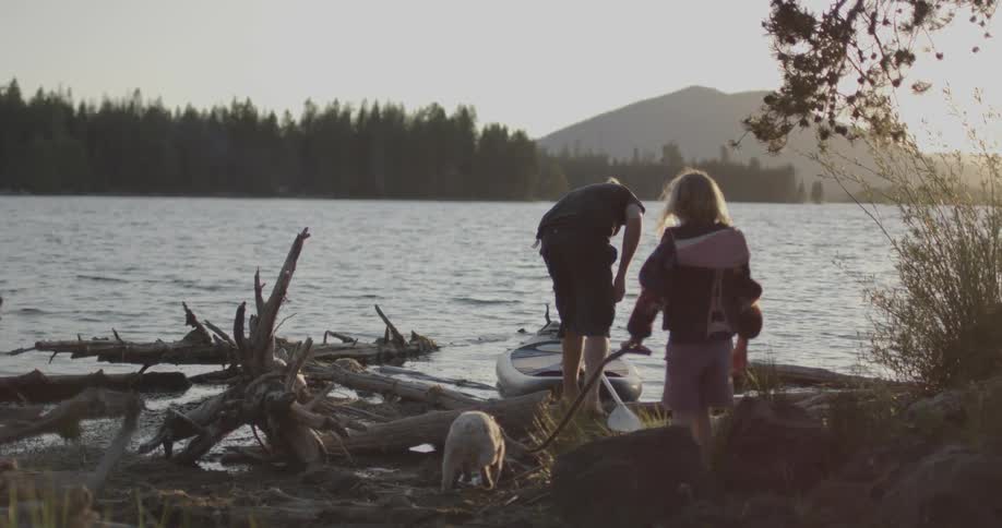 A man and child walk slowly towards the water
