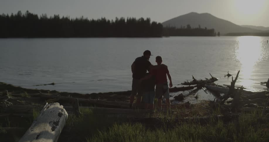 A man hugs two children near the lake