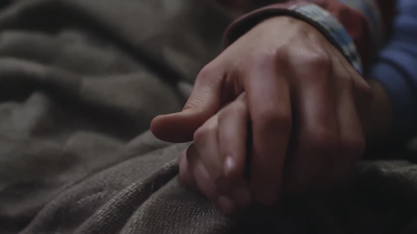 A man's hand reaches over and grasps a female's hand