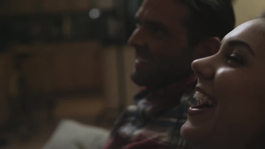 Two people smile sitting on a couch