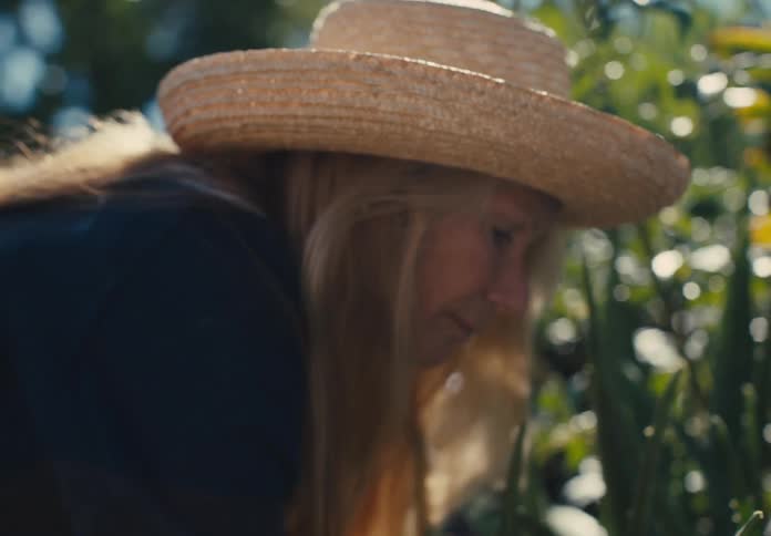 Blonde woman in hat gardening outdoors