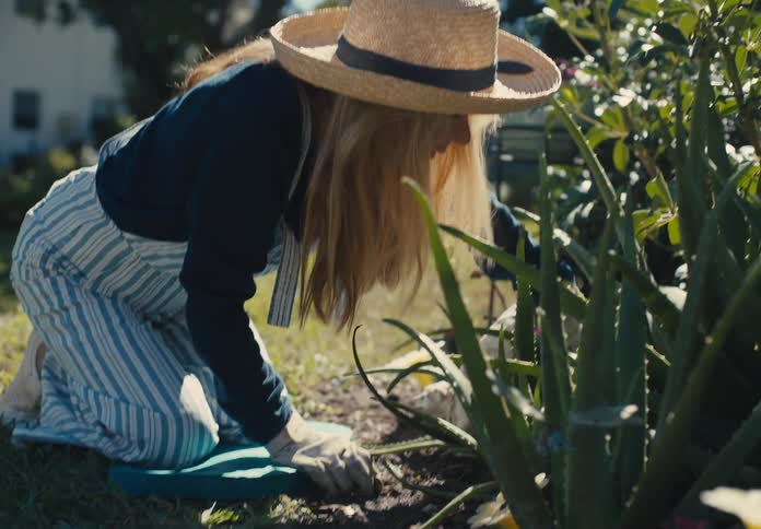 Woman crouching with a sun hat in a garden
