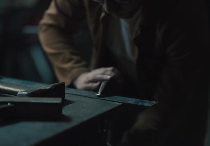 Man placing a metal tool on the corner of a table