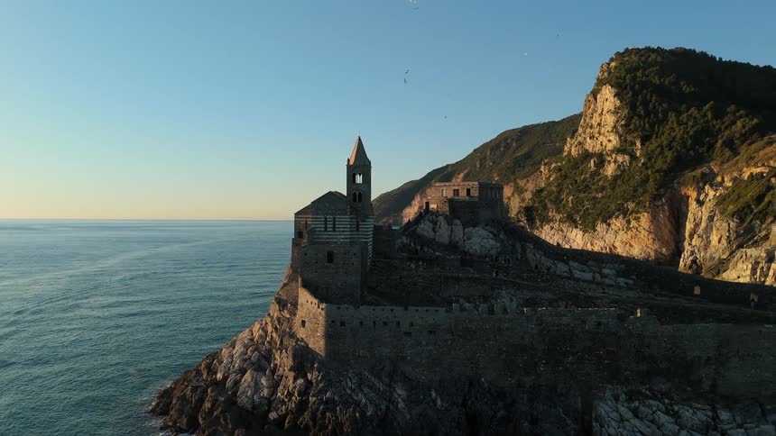 Aerial aerial scenery of a castle on an island surrounded by the sea and mountains in the background