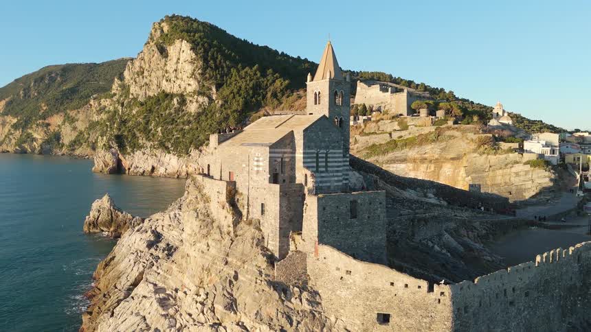 Aerial shot of a classical church with a steeple on an island surrounded by the sea