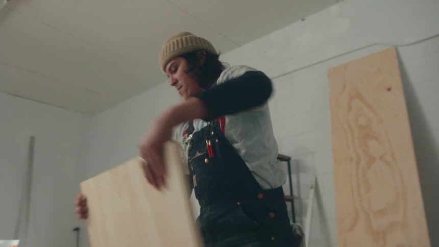 Carpenter picking up a sheet of wood
