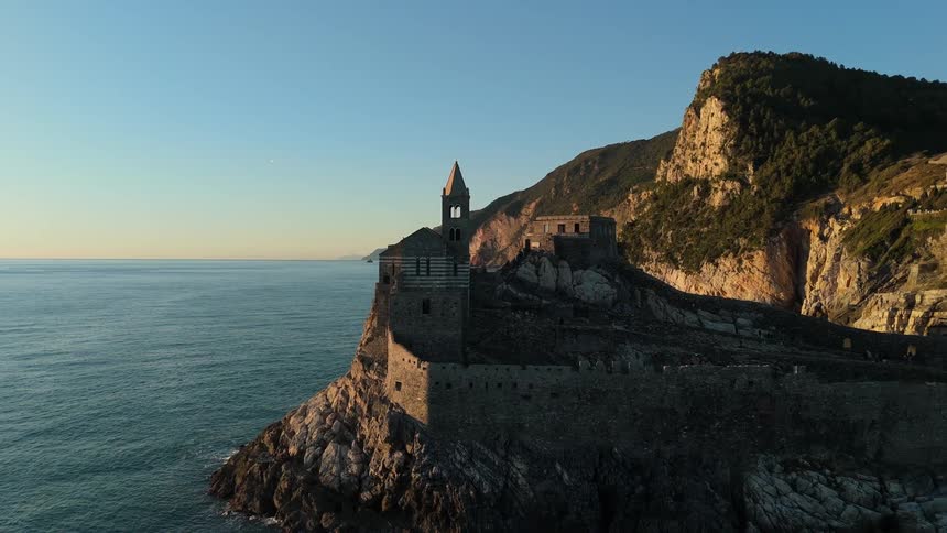 Seagulls fly near the promontory with the church of san pietro in portovenere on the rocks overlooking the sea