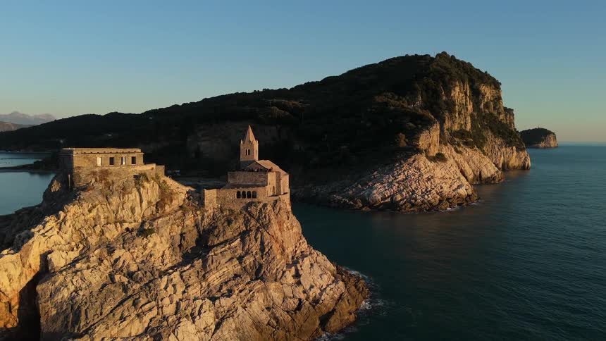 Aerial panorama of a castle on an island surrounded by sea and people walking