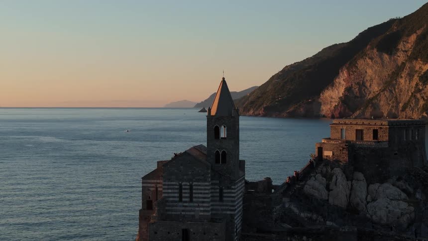 A concrete church with a small tower and facing the calm sea