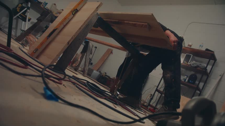 Male carpenter drops a tape measure while measuring a part of a project in a workshop