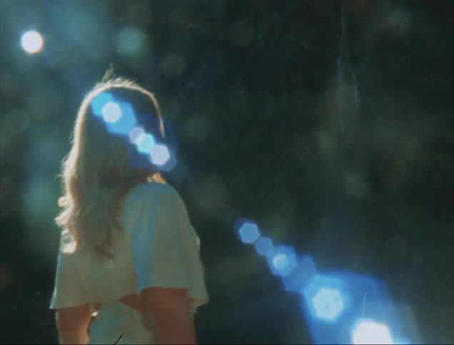 A woman is standing in the forest and the sun is shining on her