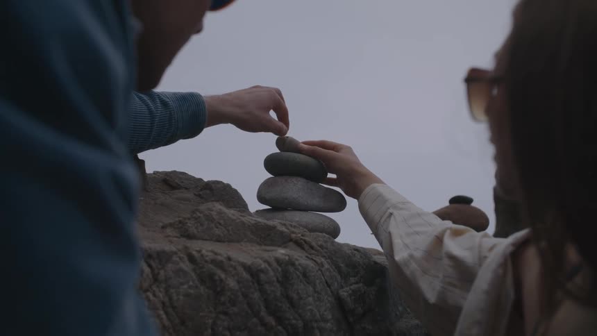A man and woman are stacking rocks