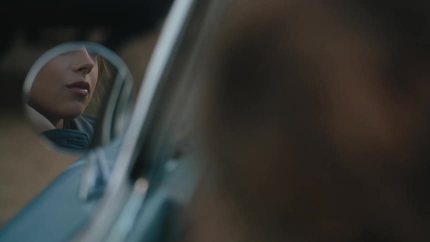 Portrait of a woman reflecting in the rearview mirror of a classic car