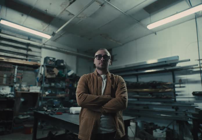 Man with glasses and arms crossed in an indoor environment of a workshop with machines and tools