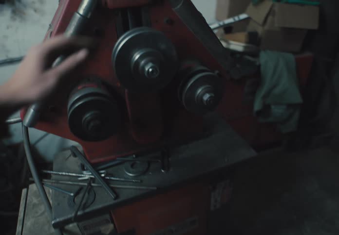 Hand picking up a tool and tightening the screw of a machine in a workshop