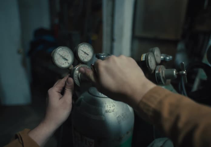 A person turns the knob on the canister to use a torch