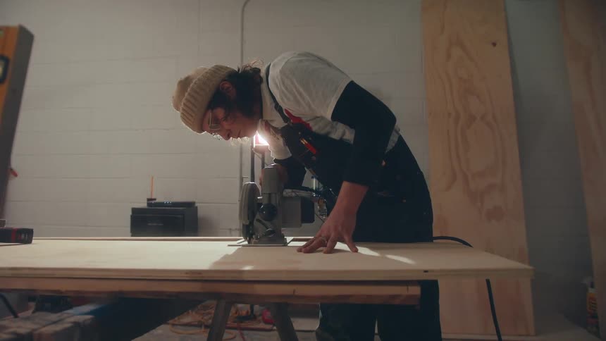 Carpenter using a makita to cut a sheet of wood
