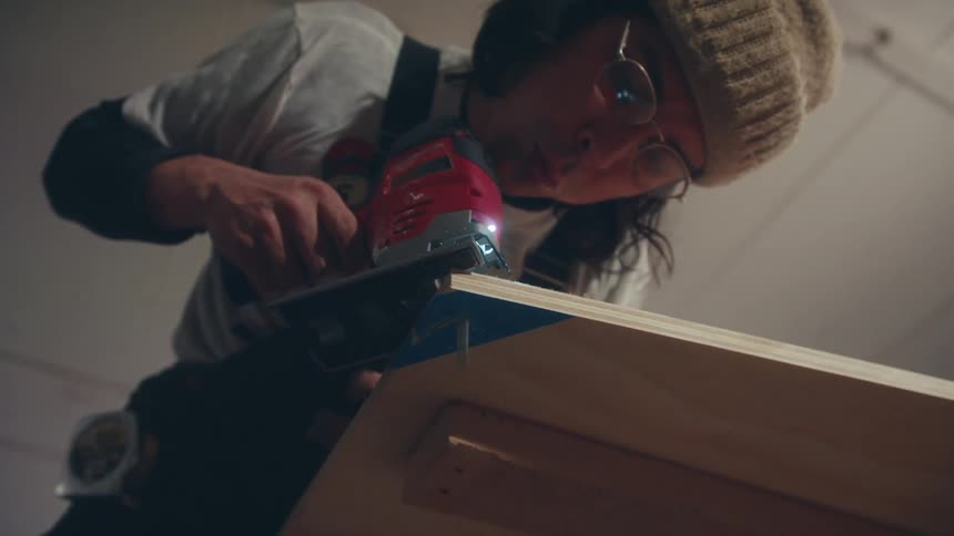 Concentrated carpenter drilling a wooden sheet