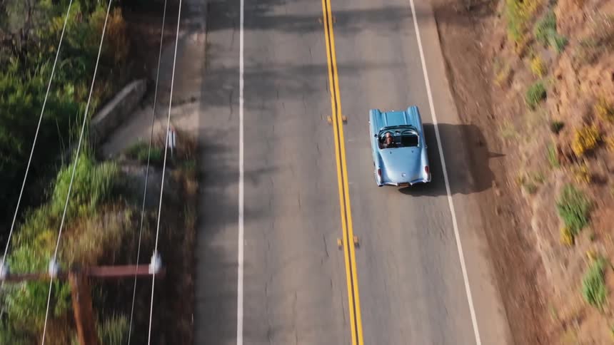 Aerial view of a convertible car traveling on a mountain road