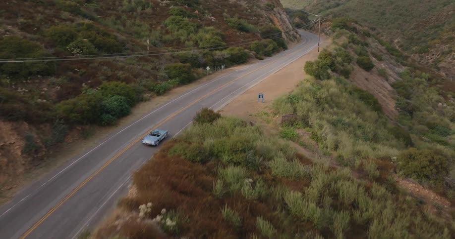 A camera follows a car driving along a winding road