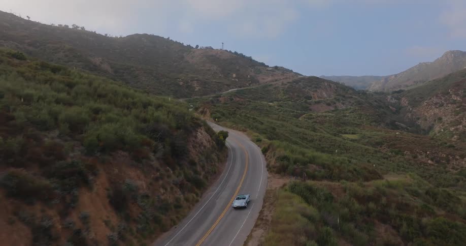 A lone car winds its way along a scenic mountain road