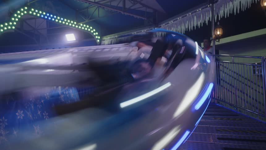 People having fun on a spinning ride at an amusement park at night