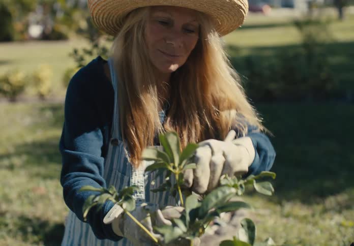 Woman with sun hat crouching in a garden