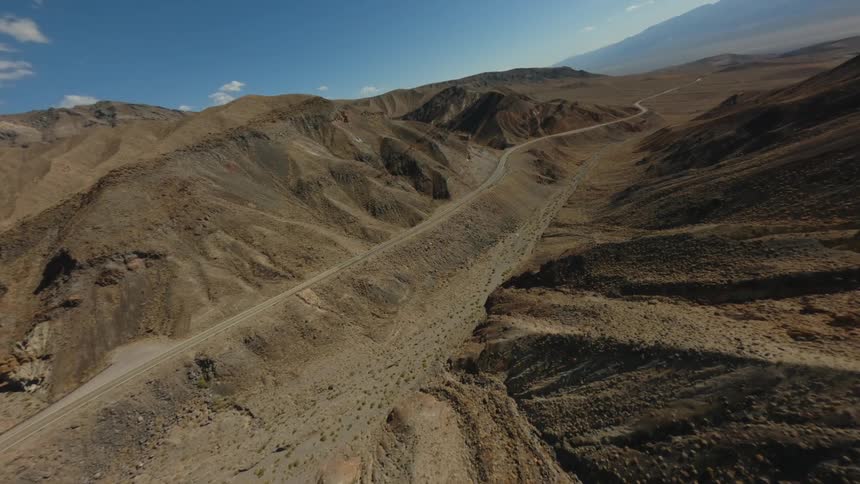 Aerial view of a highway winding through sparsely vegetated mountains