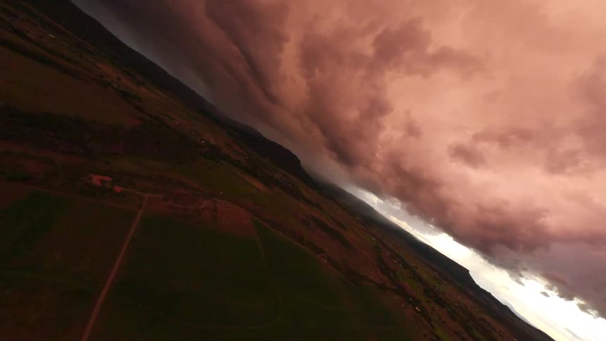 Aerial panorama of a green field and a stormy sky