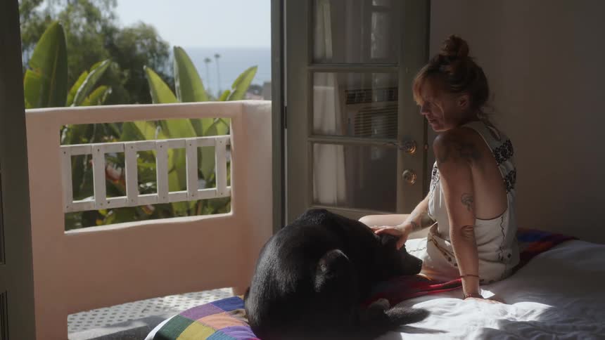 Woman sitting on bed with dog next to her