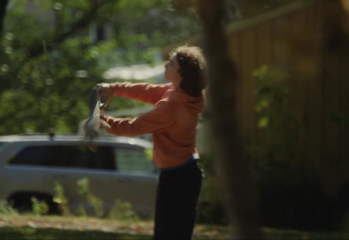 A zoomed clip of a boy holding a skateboard