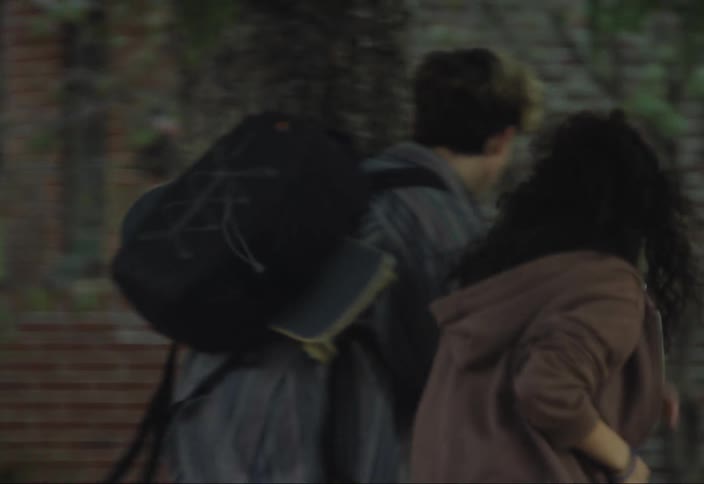 Teenager running with skateboard in hand and two other teenagers running in other direction with professional camera